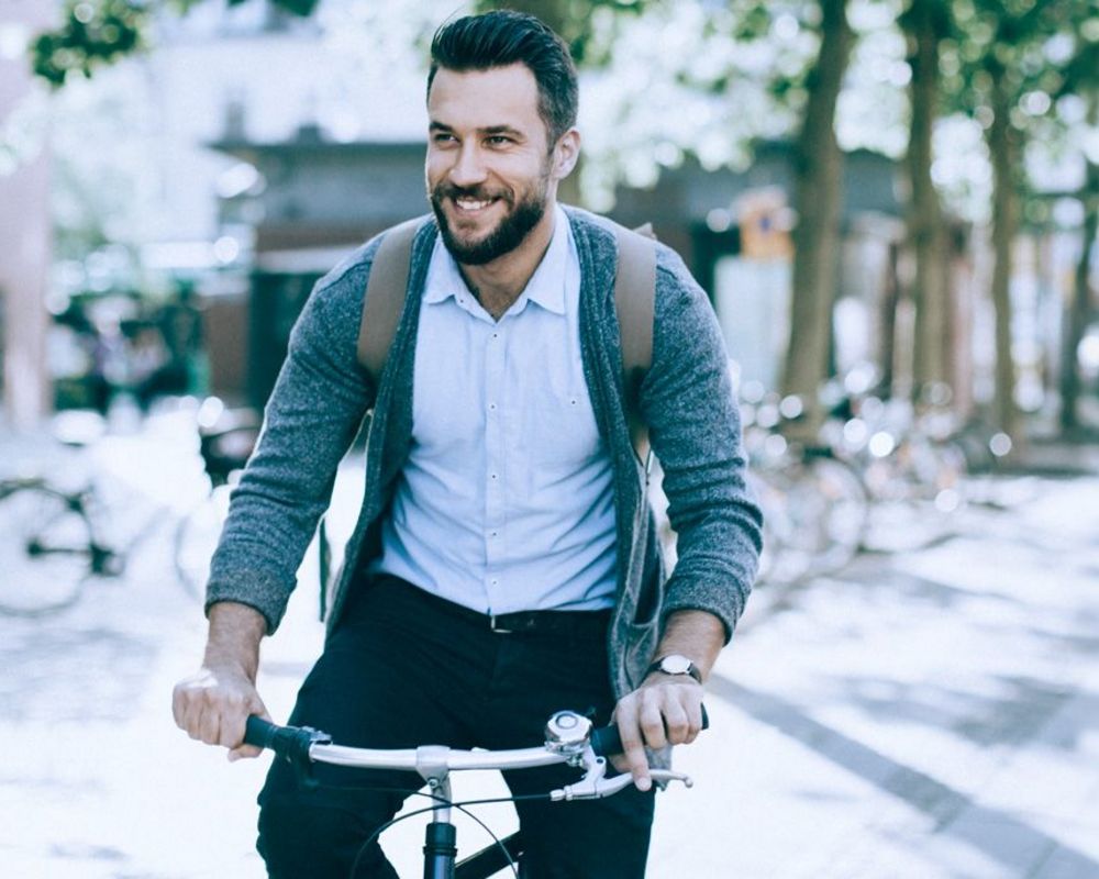 Ein Nachhaltigkeitsmanager ist mit dem Fahrrad auf dem Weg zur Arbeit. Rechts im Bild ist das ZNU Logo der Universität Witten-Herdecke eingeblendet.
