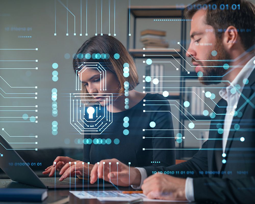 Eine KI Managerin und ein IT Administrator arbeiten an einem KI-optimierten Workflow und prüfen Compliance Aspekte an einem Computer. Im Vordergrund des Bildes sind virtuelle Prozesse und ein Sicherheitsschloss-Symbol eingeblendet.