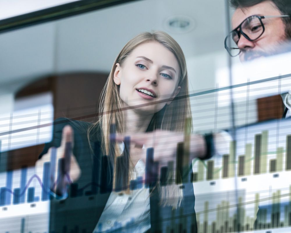 Zwei Führungskräfte betrachten ein Diagramm, um die wirtschaftliche Stabilität des Unternehmens zu analysieren.